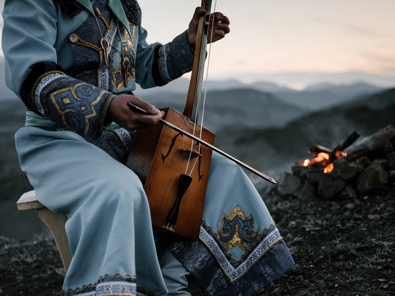 A man dressed in cultural clothing is playing an instrument.